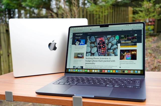 Photo of two Apple MacBook Airs, sitting one in front of the other on an outdoor table or desk.