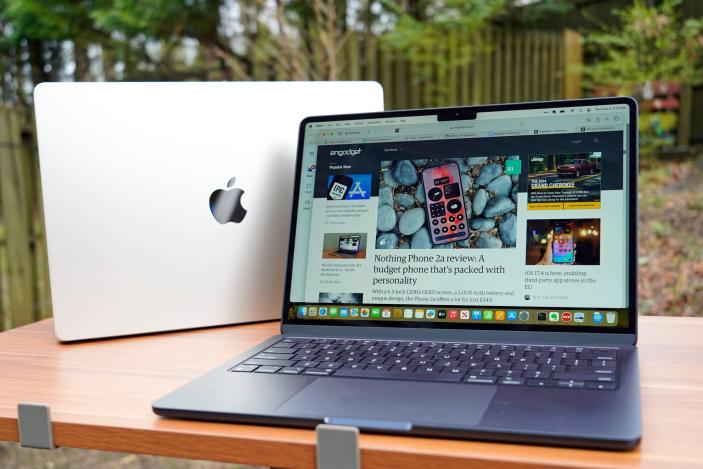 Photo of two Apple MacBook Airs, sitting one in front of the other on an outdoor table or desk.
