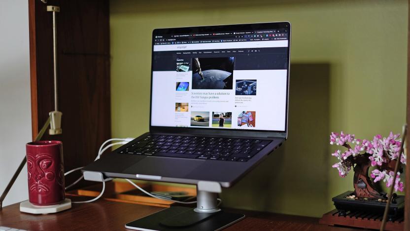Twelve South’s HiRise Pro laptop stand seen with a laptop on it in a normal desktop setup with keyboard, touchpad and a tiki-style mug.