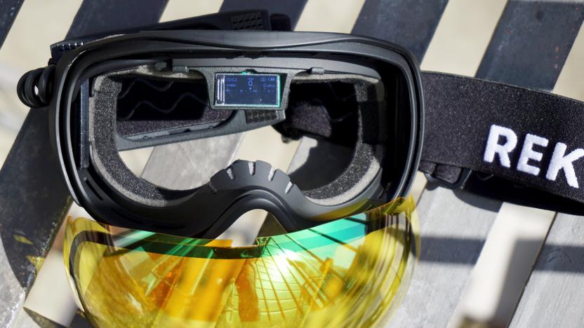 Ski Goggles with yellow lenses that have been removes and a small display in the middle of the frames.                               