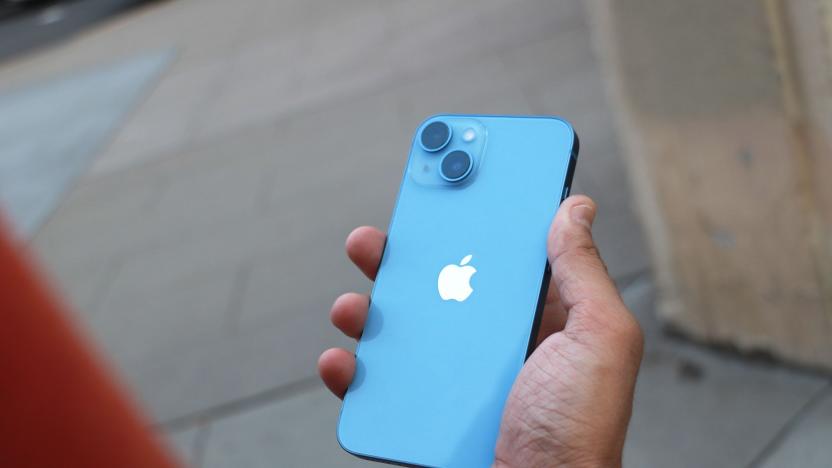 The iPhone 14 held in a hand with its rear cameras facing out.