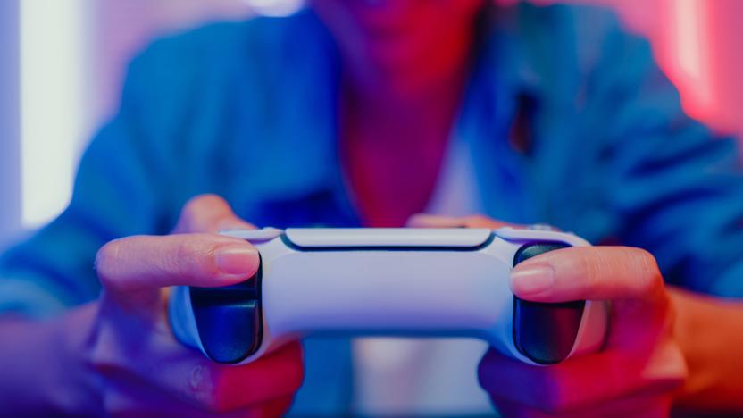 Close up of young Asian woman playing video game console in neon lights living room at home. Gamer lifestyle concept.
