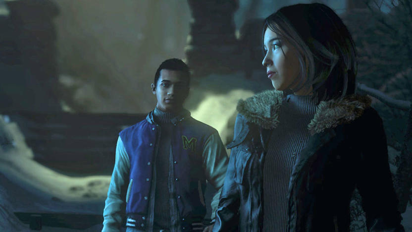 Two characters stand near each other, one a boy in a letterman's jacket looks at a woman standing in front of him and she's glancing to the side in this still from the video game Until Dawn. 