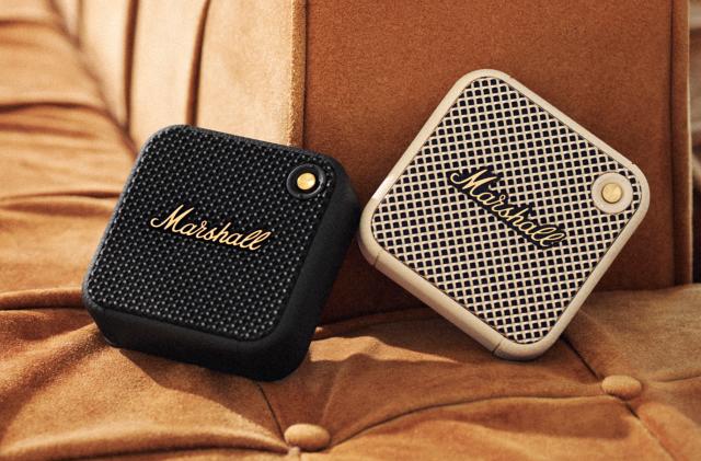 Two of the Marshall Willen micro Bluetooth speakers on a fabric banquet.