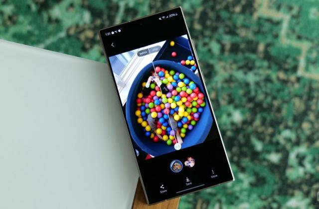 Photo of the Galaxy S24’s AI-based photo editing feature on the Galaxy S24 Ultra. A colorful ball pit is viewed in split screen before and after edits. The phone sits on the corner of a table.