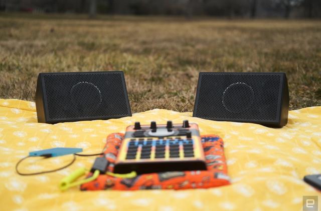 AIAIAI Unit 4 Wireless+ studio monitors on a picnic blanket in a park along with an SP-404 MKII with an adorable Speak & Spell skin. 