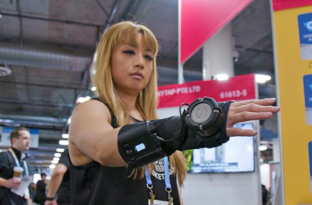 A woman wearing the GyroGlove at the CES 2024, holding her hand out. 