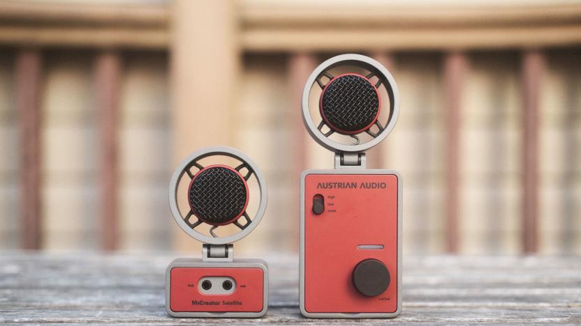 The Austrian Audio MiCreator in two parts: Two round microphones sit atop one smaller and one larger rectangular bases facing the camera and seen on a weathered wooden outdoor table.