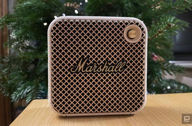 A white Marshall Willen Bluetooth speaker sits on a table with a holiday tree in the background.
