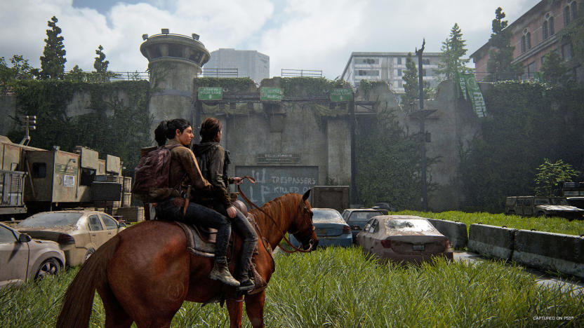 Two people ride on a single horse in an urban scene with abandoned cars that's overrun by tall grass and trees in this scene from the video game The Last of Us Part II Remastered.
