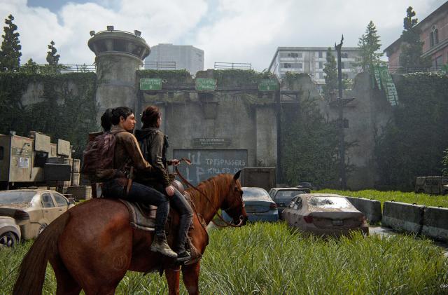 Two people ride on a single horse in an urban scene with abandoned cars that's overrun by tall grass and trees in this scene from the video game The Last of Us Part II Remastered.
