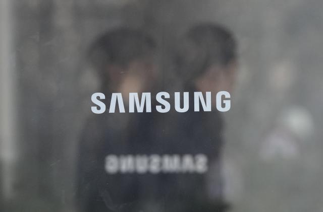 Employees walk past logos of the Samsung Electronics Co. at its office in Seoul, South Korea, Wednesday, Jan. 31, 2024. Samsung Electronics on Wednesday reported an annual 34% decline in operating profit for the last quarter as sluggish demands for its TVs and other consumer electronics products offset hard-won gains from a slowly recovering computer chip market. (AP Photo/Ahn Young-joon)