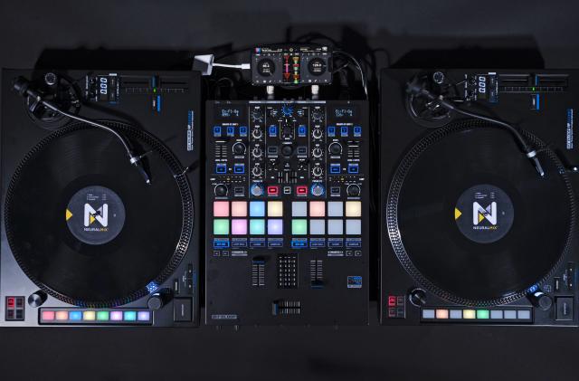 An overhead view of a DJ setup showing two turntables with control discs on them alongside a Reloop DJ mixer and an iPhone which now supports a digital vinyl system (DVS). 