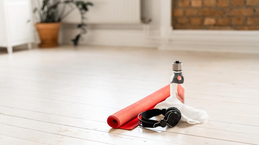 A red yoga mat on white hardwood floor in a domestic living room at home. Ready to be used in some home exercises.