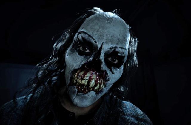 A figure wearing a creepy and bloody evil clown mask is shown in the promo image for the video game Until Dawn.