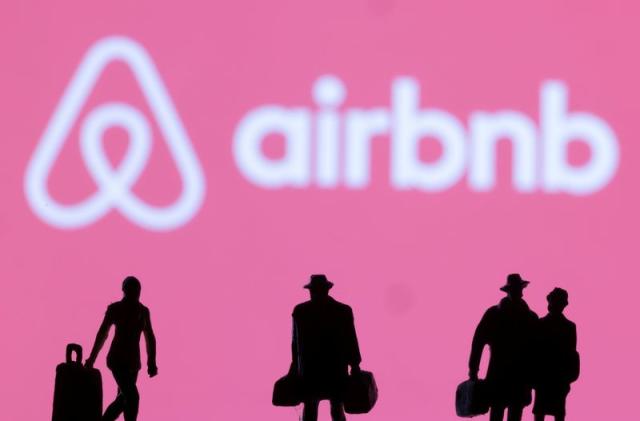 Figurines are seen in front of displayed Airbnb logo