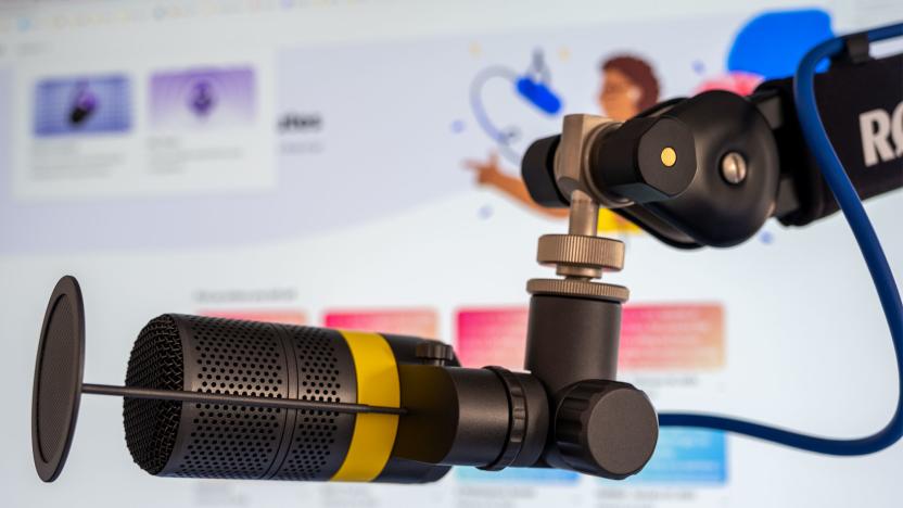 A microphone is pictured infront of a monitor showing Adobe's Podcast tool.