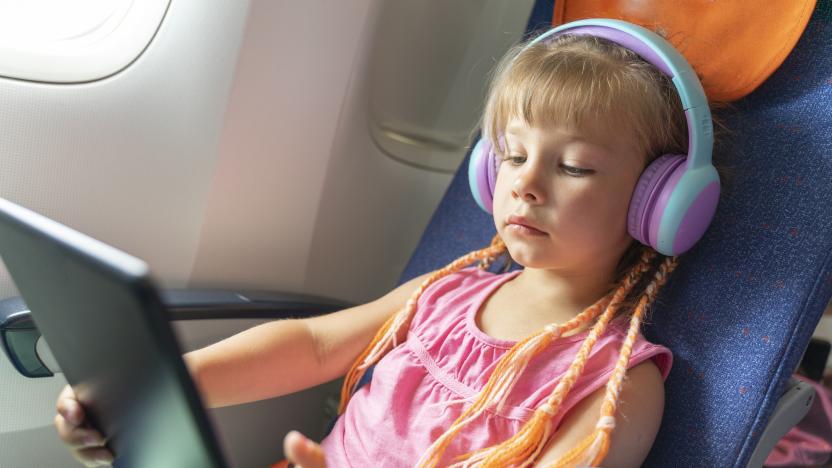Caucasian girl with headphones watching and listening in flight entertainment on board an airplane