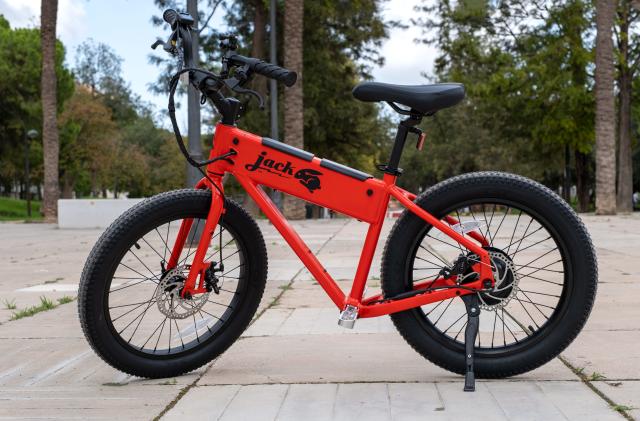The red Jackrabbit mini e-bike is pictured riderless in a park.