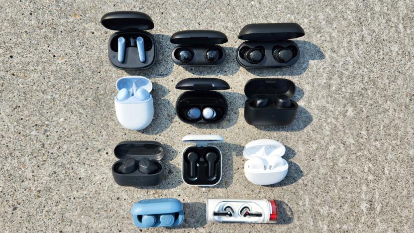 A selection of wireless earbuds sit organized in rows on a granite background.