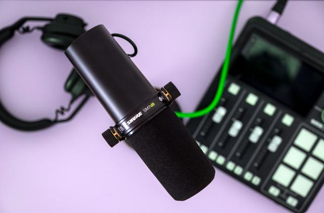 The Shure SM7dB microphone is pictured above a Rodecaster Duo and a pair of headphones.
